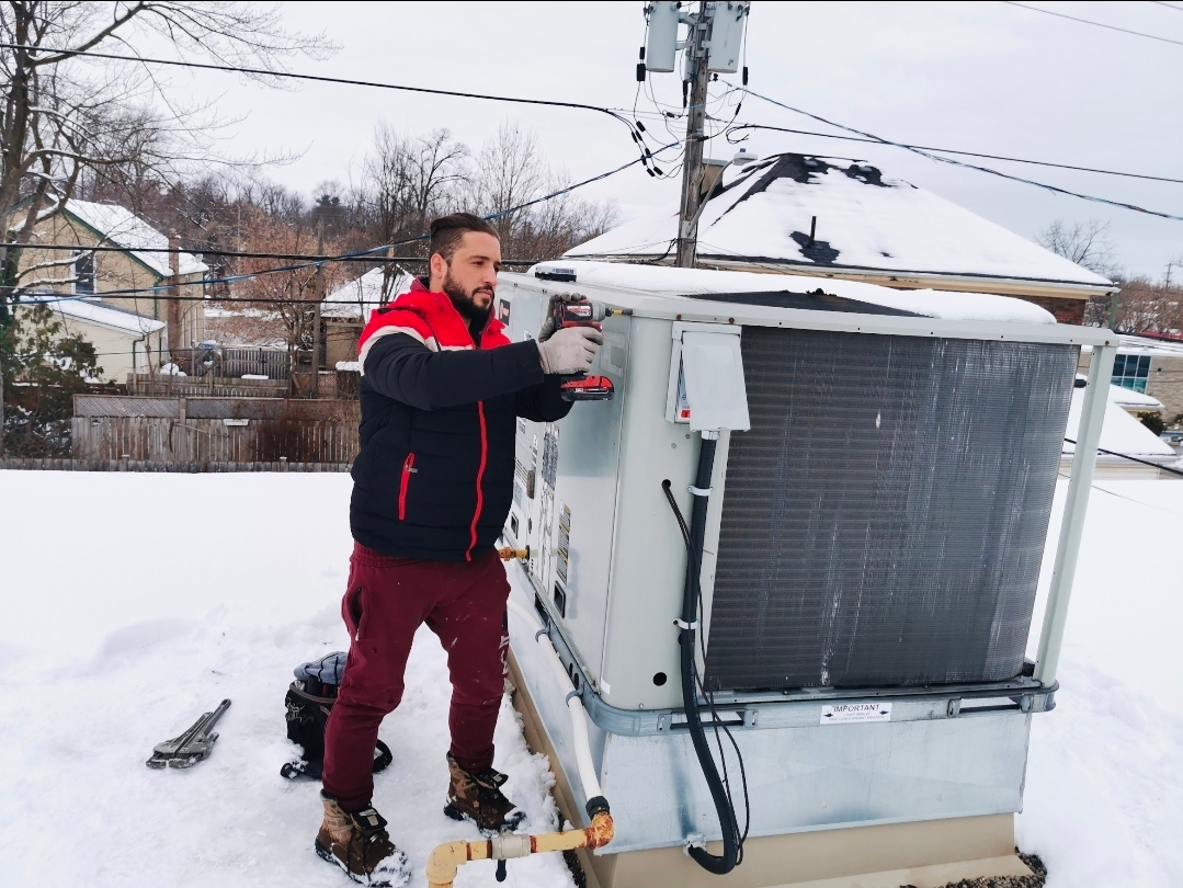 Abdullah Ghzail repairing rooftop HVAC unit in snow – Owner & Lead TSSA-Certified Technician at Hawana HVAC Solutions London Ontario