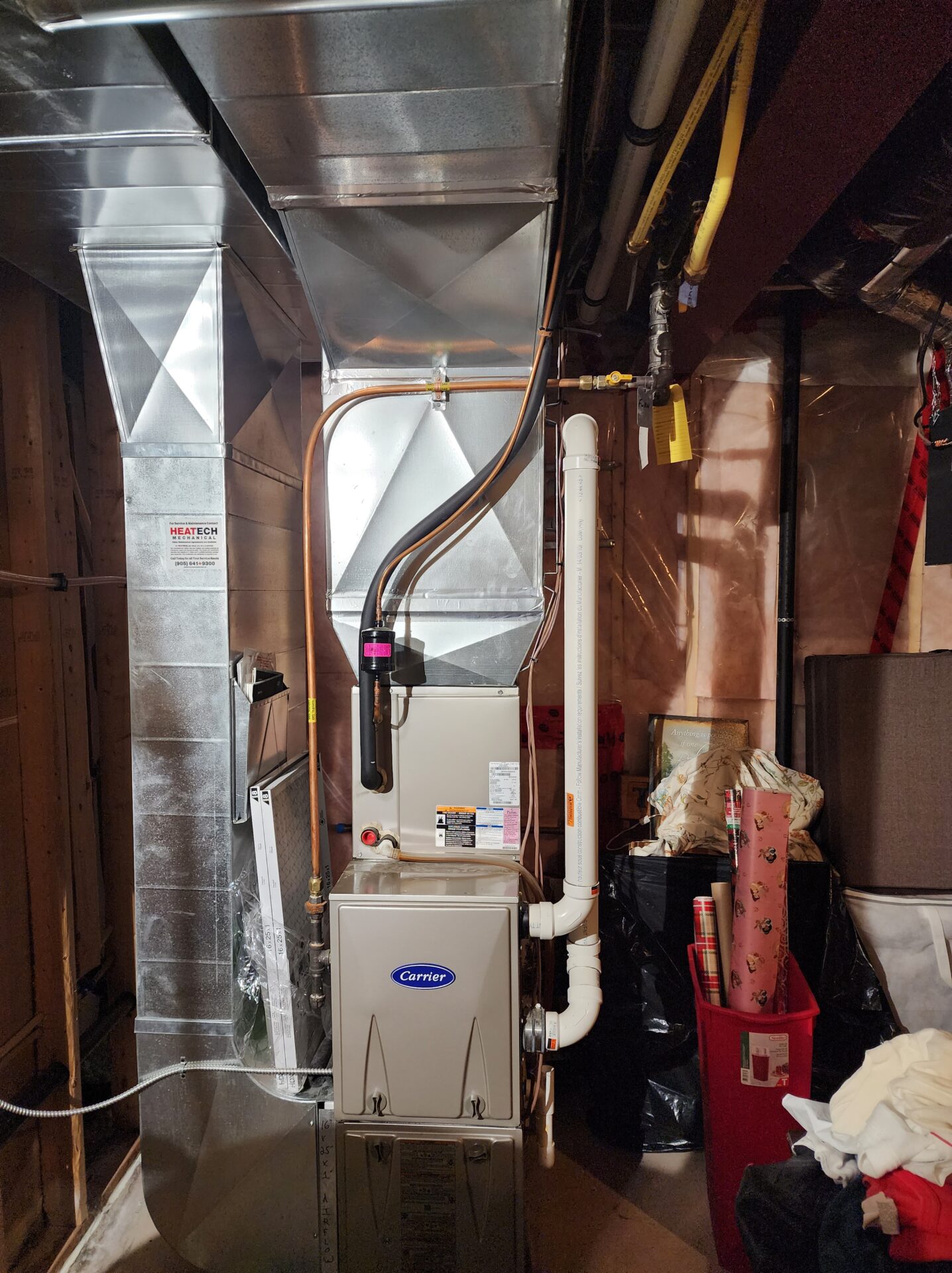 A meticulously installed Carrier high-efficiency gas furnace with custom sheet metal plenums and PVC exhaust pipes.