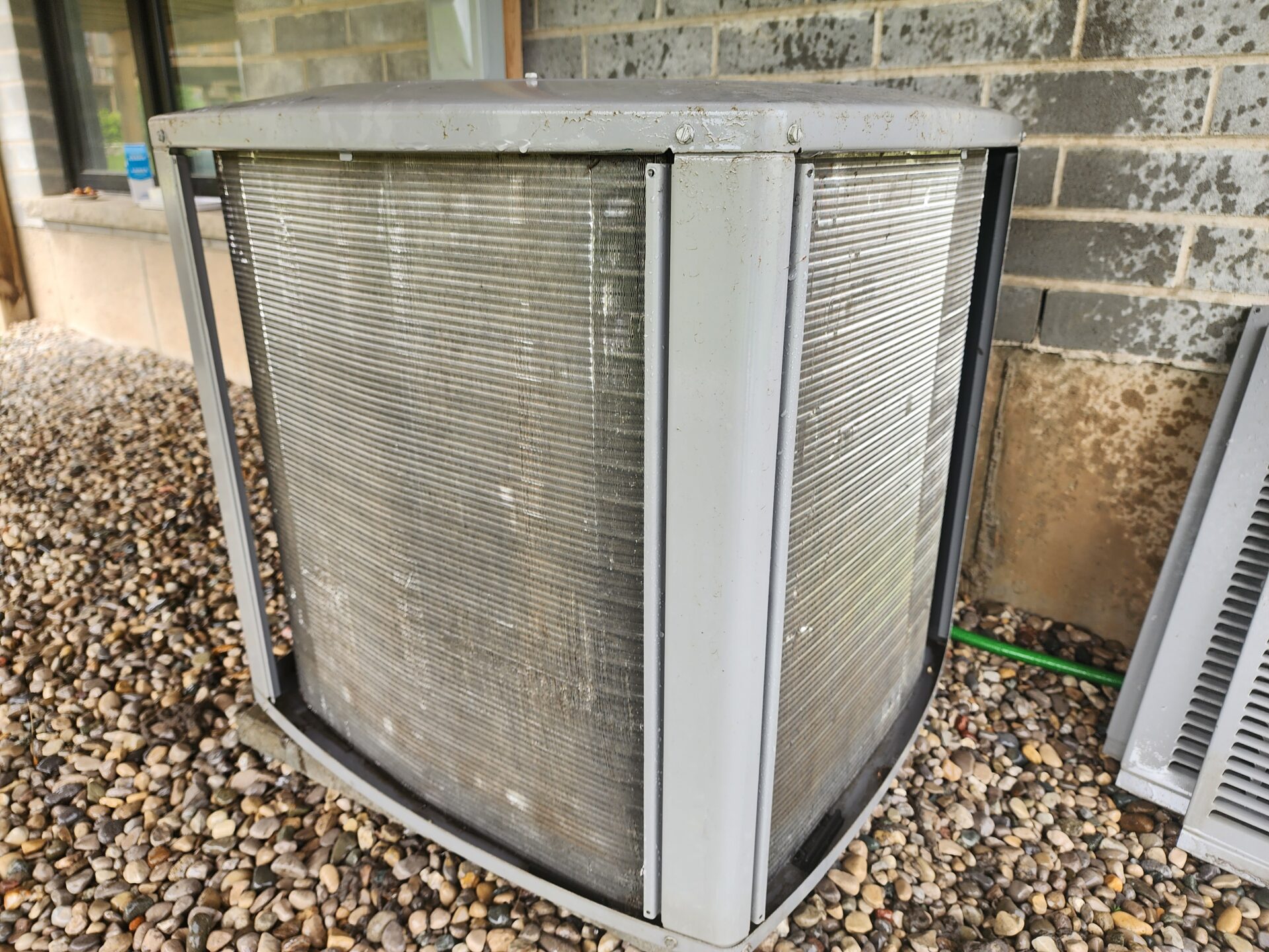 A clean residential air conditioner condenser coil with shiny aluminum fins, shown with its outer panels removed.