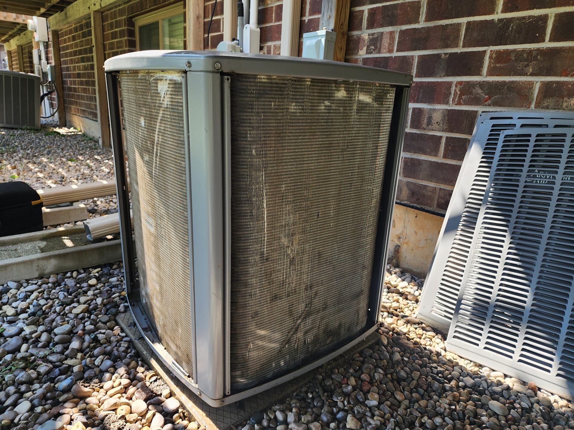 A severely dirty and clogged residential air conditioning condenser coil with its outer panels removed.