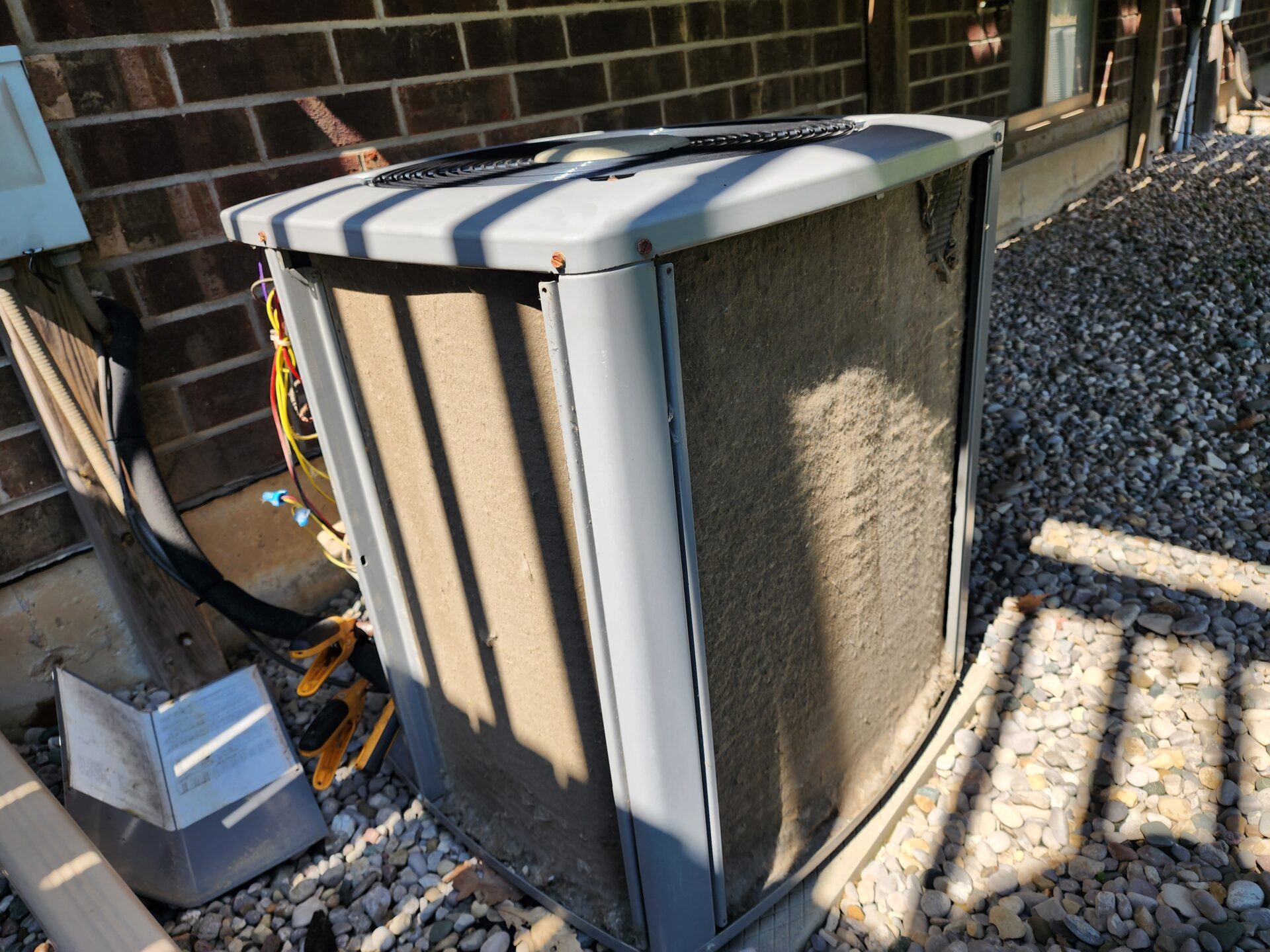 A severely dirty and clogged residential air conditioning condenser coil with its outer panels removed.