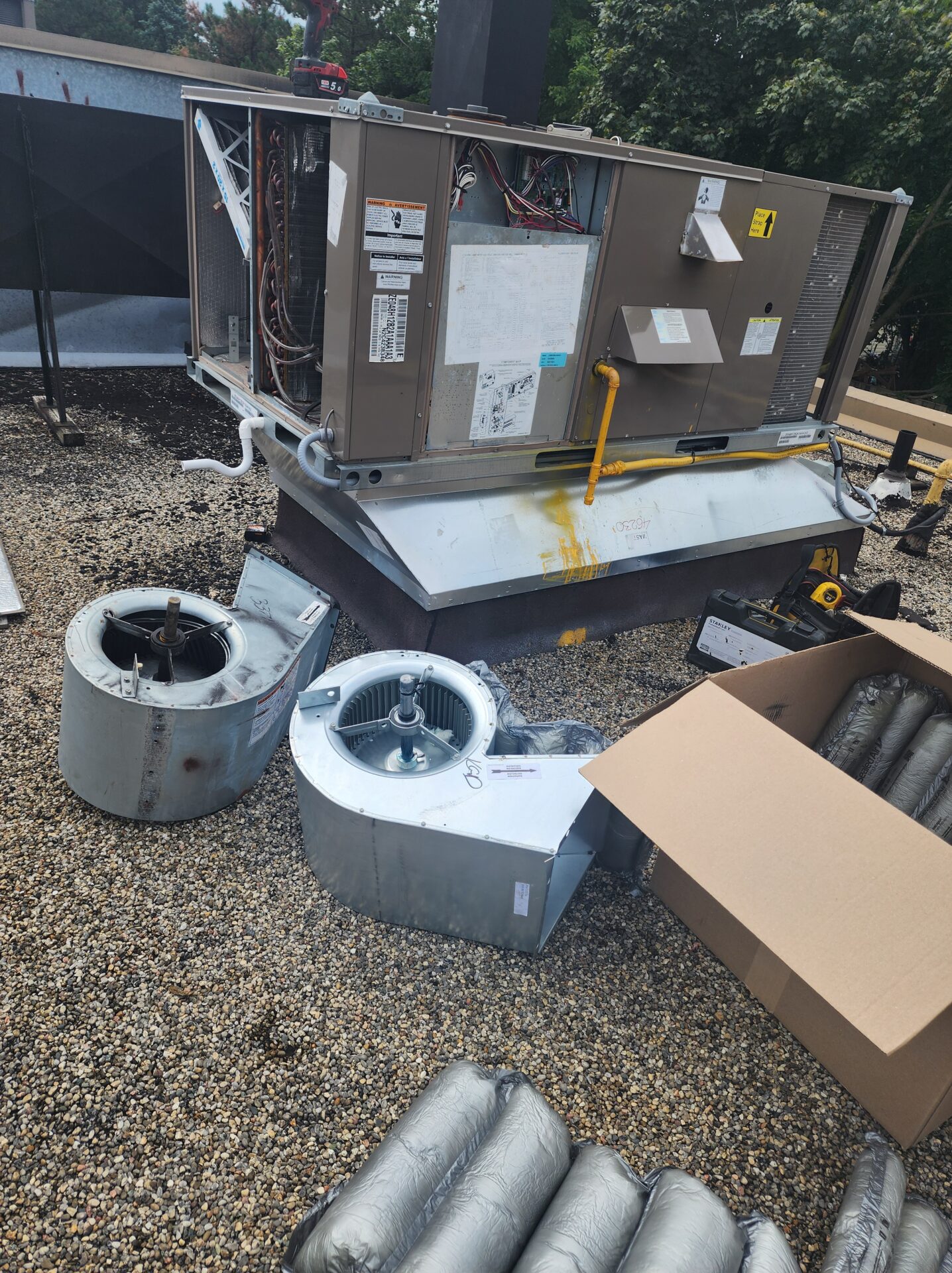 Two large commercial HVAC blower wheel assemblies removed from a rooftop unit during extensive maintenance.
