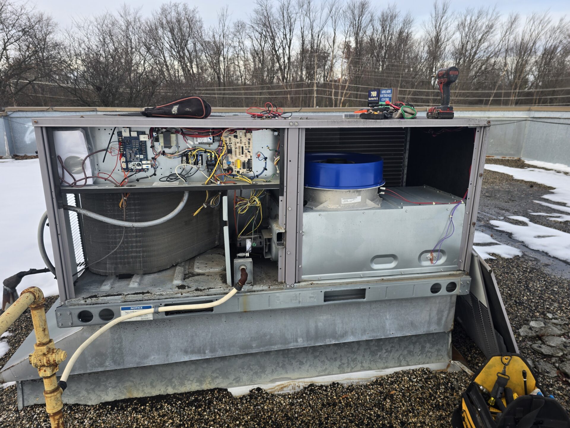 The internal electrical panel, control board, and blower motor of a commercial rooftop HVAC unit exposed for diagnostic testing.