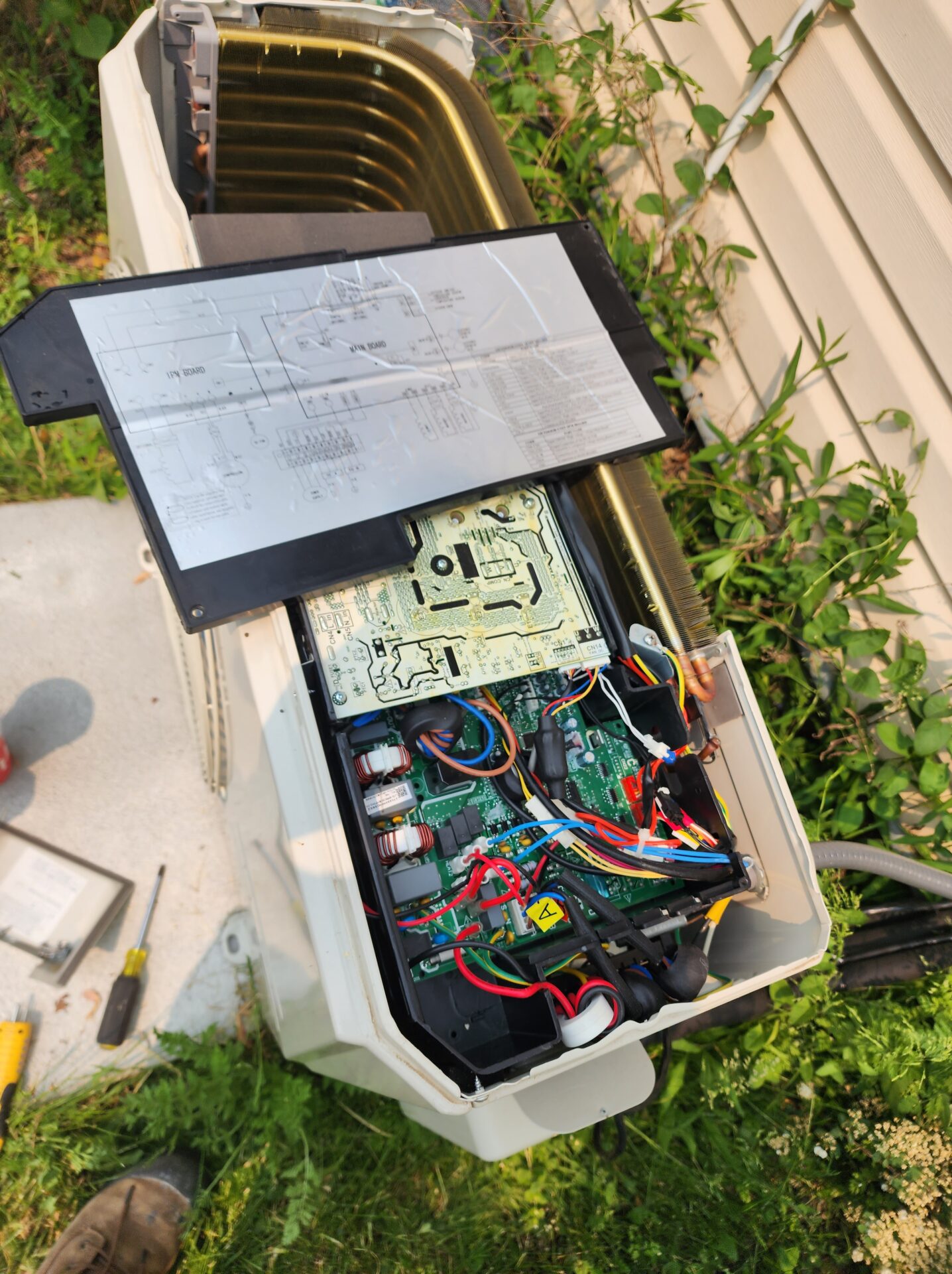 Open access panel revealing the internal inverter control board and wiring of a high-efficiency heat pump.