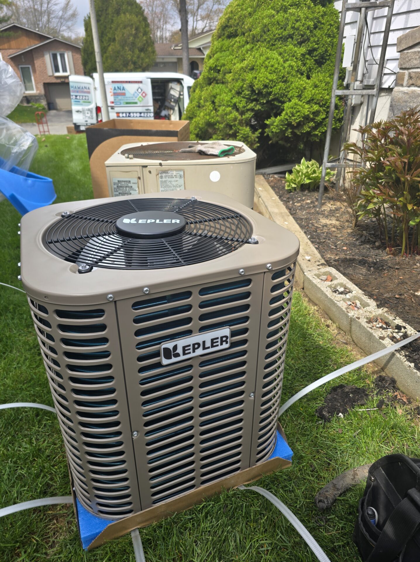Newly installed Kepler air conditioning condenser placed on a leveling pad, with the old Lennox unit disconnected in the background.