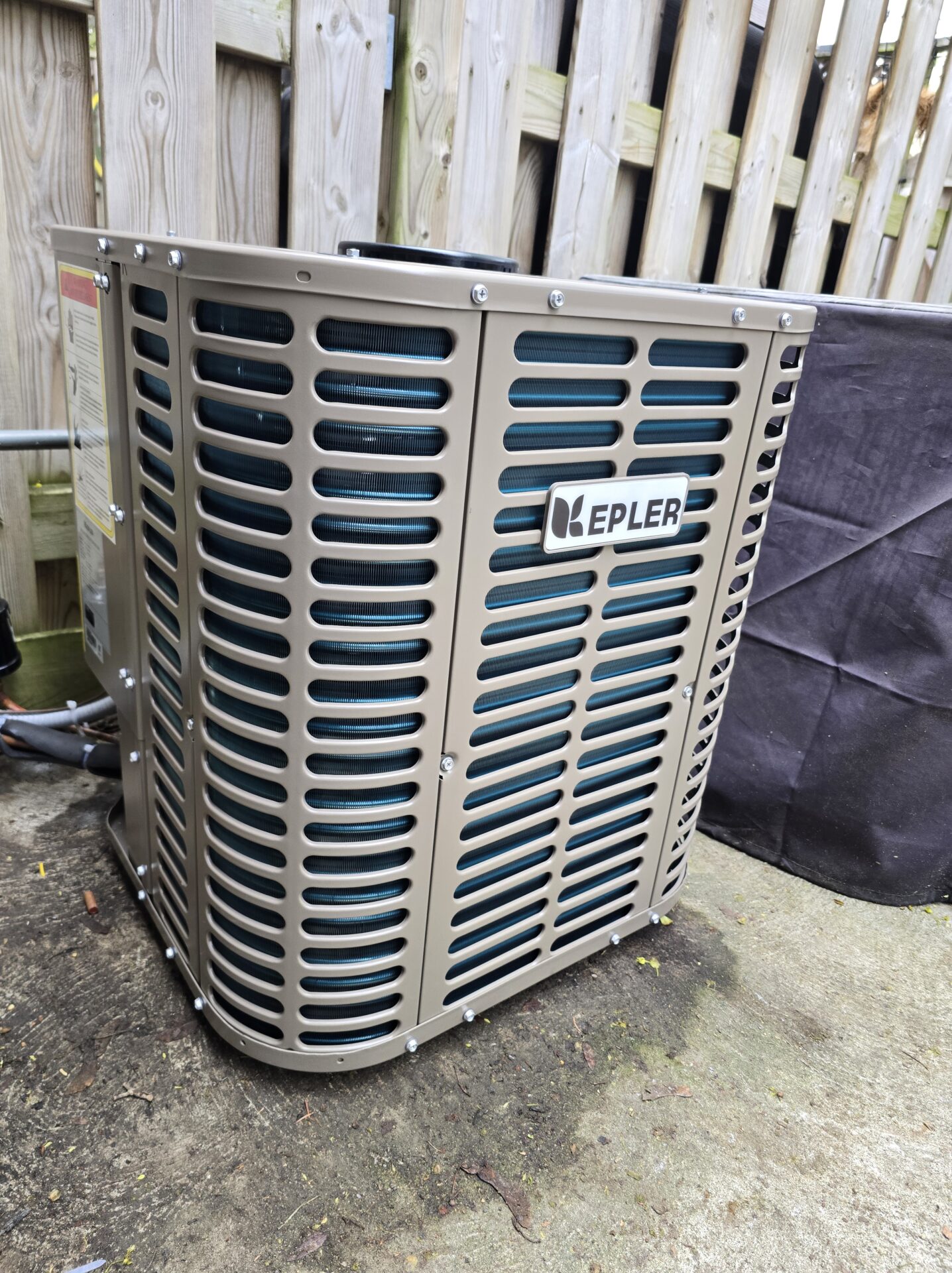 A newly installed KEPLER air conditioning condenser unit sitting securely on a concrete pad outdoors.