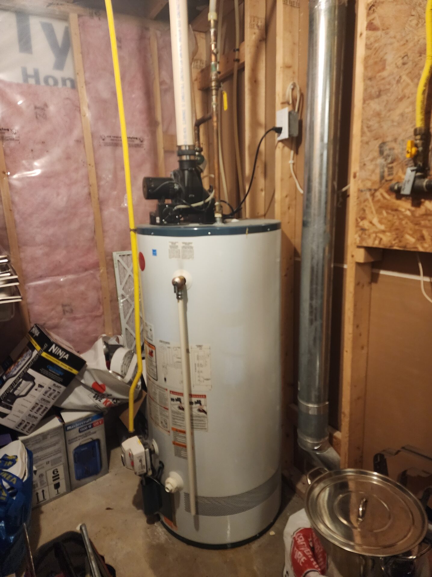 Standard power vent residential gas hot water heater tank fully installed with gas piping and exhaust venting in a utility room.