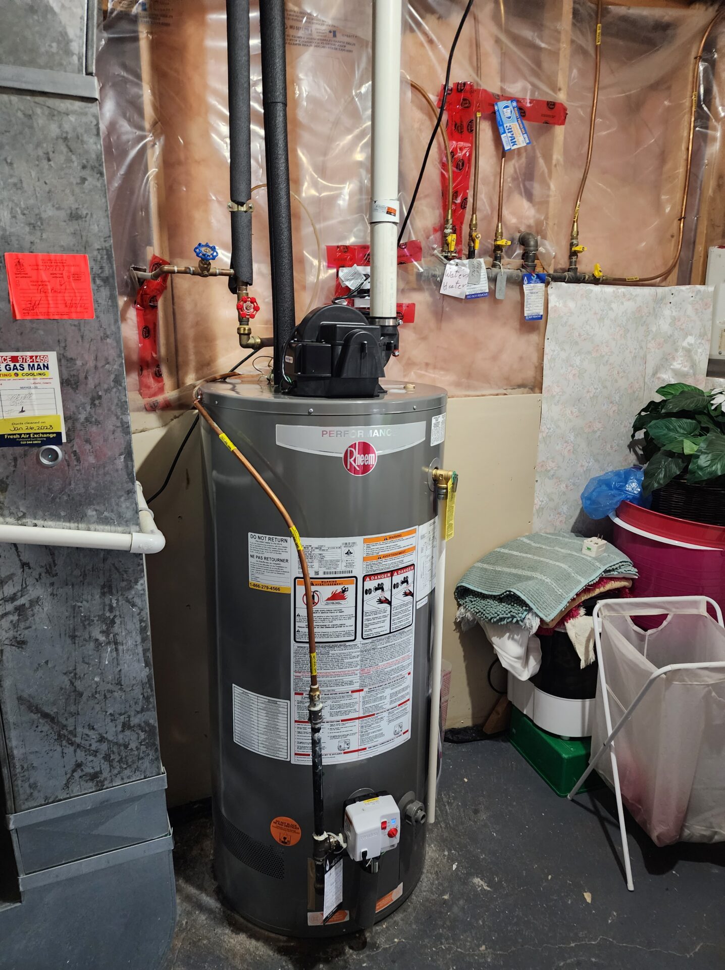 A professionally installed Rheem Performance series power-vented gas water heater in a basement utility room.